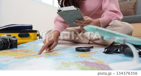 Travel Planning. Woman organizing travel essentials with a map and passport. Travel Planning. Woman organizing travel essentials with a map and passport. 134376356