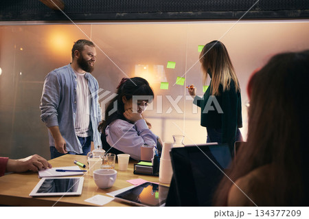 Coworkers brainstorming startup ideas with sticky notes in modern office. 134377209