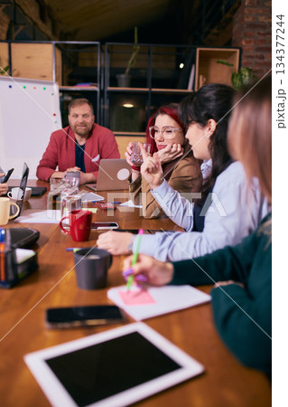 Coworkers focusing on tasks during creative team meeting. Coworkers focusing on tasks during creative team meeting. 134377244
