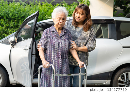 Caregiver help Asian elderly woman disability patient get in her car. 134377759