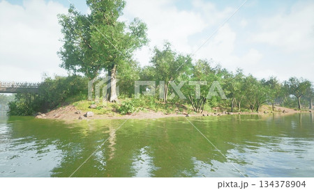 A peaceful riverbank scene features vibrant green trees reflecting in calm water. Soft sunlight filters through foliage, creating a serene atmosphere perfect for relaxation and nature lovers. 134378904