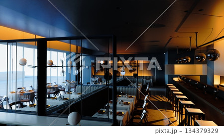 Warm tones fill the stylish dining area, highlighting sleek tables and modern furnishings. Subtle shadows dance on the walls as the early evening light creates a cozy atmosphere for diners. 134379329