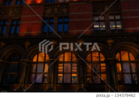 Building with arched windows lit at night in a city setting Building with arched windows lit at night in a city setting 134379462