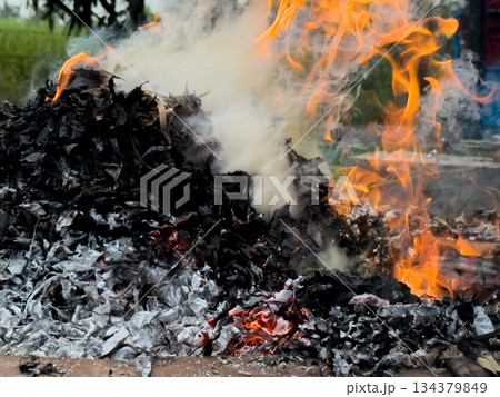 dangerously hot orange and red flames with dense black smoke consuming wood and embers 134379849