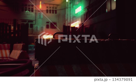 A vibrant night scene showcases glowing neon lights reflecting off wet pavement. The city streets are filled with shadows, creating a mysterious and captivating urban vibe. 134379891