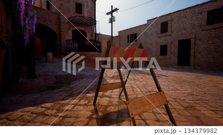 In a charming village square, wooden construction barriers mark an area under repair. The sunlight casts a warm glow over cobblestones and rustic buildings, while flowers add color nearby. In a charming village square, wooden construction barriers mark an area under repair. The sunlight casts a warm glow over cobblestones and rustic buildings, while flowers add color nearby. 134379982