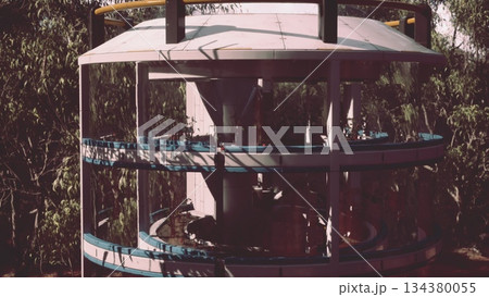 A unique architectural design comes to life amidst greenery. Workers collaborate at various levels, showcasing teamwork and innovation. The structure features circular layers and transparent elements. A unique architectural design comes to life amidst greenery. Workers collaborate at various levels, showcasing teamwork and innovation. The structure features circular layers and transparent elements. 134380055