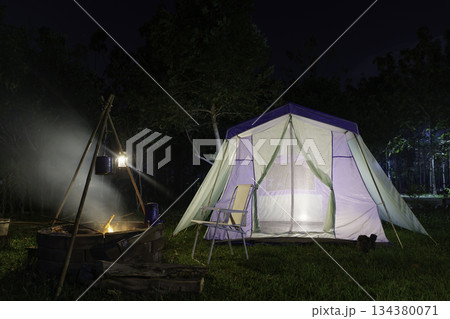 Nighttime camping tent in a forest clearing surrounded by nature Nighttime camping tent in a forest clearing surrounded by nature 134380071