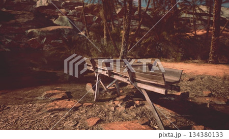 A rustic wooden boat sits peacefully by the edge of some calm waters. Palm trees sway gently in the warm breeze while rocks line the tranquil shore, creating a serene atmosphere. A rustic wooden boat sits peacefully by the edge of some calm waters. Palm trees sway gently in the warm breeze while rocks line the tranquil shore, creating a serene atmosphere. 134380133
