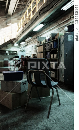 A worn chair sits on a stack of boxes in a dusty workshop. Shelves hold scattered tools and materials, while sunlight softly filters through the high windows, creating an atmosphere of nostalgia. 134380145