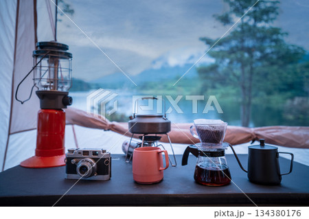 Coffee drip set for camping inside a tent, looking out to the mountain and lake view. Coffee drip set for camping inside a tent, looking out to the mountain and lake view. 134380176
