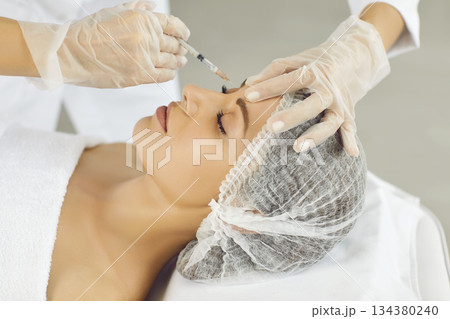 Cosmetologist making rejuvenation anti wrinkle injection in woman face skin in a beauty spa salon. Cosmetologist making rejuvenation anti wrinkle injection in woman face skin in a beauty spa salon. 134380240