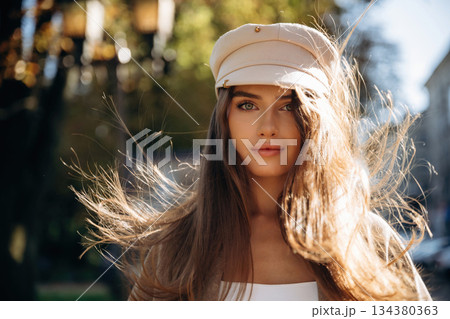 In white hat. Beautiful woman is outdoors in the town In white hat. Beautiful woman is outdoors in the town 134380363