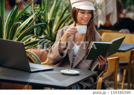Reading the information. Beautiful young woman is outdoors of the restaurant by the table Reading the information. Beautiful young woman is outdoors of the restaurant by the table 134380390