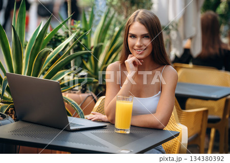 Feeling good, with orange juice. Beautiful young woman is outdoors of the restaurant by the table 134380392