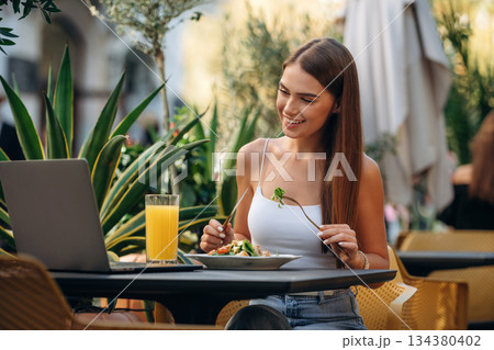 Outdoors of the restaurant. Beautiful young woman is sitting by the table Outdoors of the restaurant. Beautiful young woman is sitting by the table 134380402
