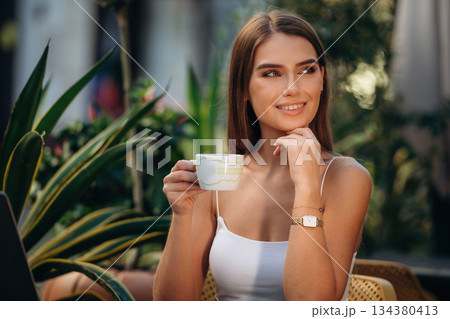 Happy smile, sitting. Beautiful young woman is outdoors of the restaurant by the table Happy smile, sitting. Beautiful young woman is outdoors of the restaurant by the table 134380413