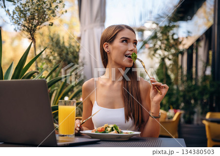 Tasting delicious food. Beautiful young woman is outdoors of the restaurant by the table Tasting delicious food. Beautiful young woman is outdoors of the restaurant by the table 134380503