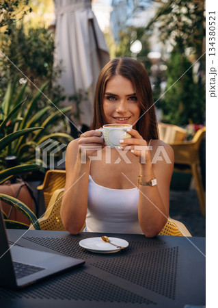 Cup of drink. Beautiful young woman is outdoors of the restaurant by the table Cup of drink. Beautiful young woman is outdoors of the restaurant by the table 134380521
