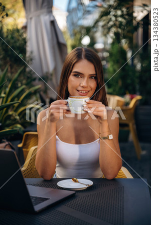 Cup of drink. Beautiful young woman is outdoors of the restaurant by the table Cup of drink. Beautiful young woman is outdoors of the restaurant by the table 134380523