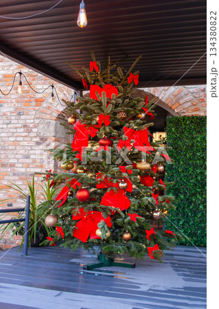 Decorated Christmas tree with red bows and ornaments in outdoor setting Decorated Christmas tree with red bows and ornaments in outdoor setting 134380822