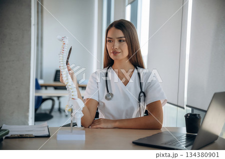 Spine model on the table. Professional female doctor in the clinic indoors 134380901