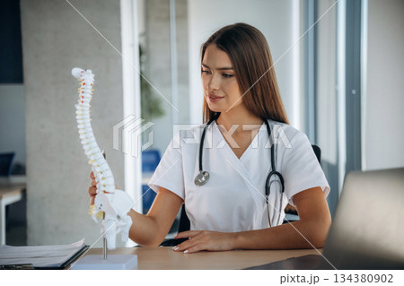 Spine model on the table. Professional female doctor in the clinic indoors 134380902