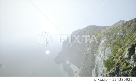 Morning light softly illuminates the rugged cliffs overlooking a calm ocean. Waves gently lap at the shore, while lush greenery adds vibrant color to the landscape. Morning light softly illuminates the rugged cliffs overlooking a calm ocean. Waves gently lap at the shore, while lush greenery adds vibrant color to the landscape. 134380923