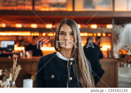 People are behind at background. Restaurant owner or manager is standing indoors People are behind at background. Restaurant owner or manager is standing indoors 134381130