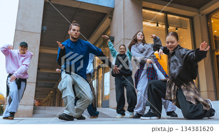 Group of street dancers practicing expressive moves in city plaza setting. Group of street dancers practicing expressive moves in city plaza setting. 134381620