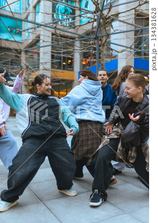 Hip hop dancers practicing moves in city walkway during casual rehearsal. 134381628