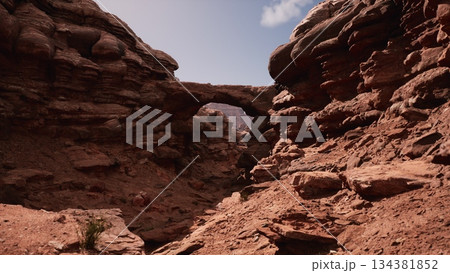 In a vast desert, majestic rock formations rise against a clear blue sky. The sun bathes the landscape in warmth, revealing intricate textures and colors in the stone. Natures beauty abounds. 134381852