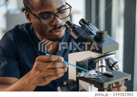 Focused on job. Scientist is working indoors, microscope is on the table 134381902
