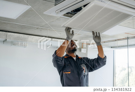Fixing the ventilation. Repairman is indoors in the modern office 134381922