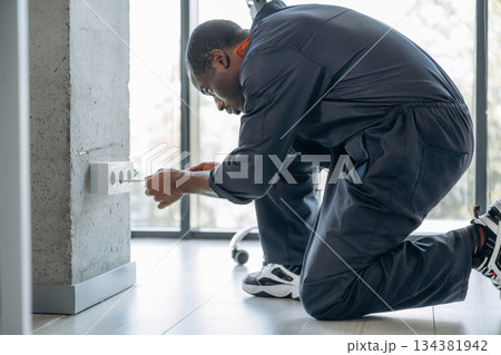 Process of installation of the socket. Repairman is indoors in the modern office Process of installation of the socket. Repairman is indoors in the modern office 134381942