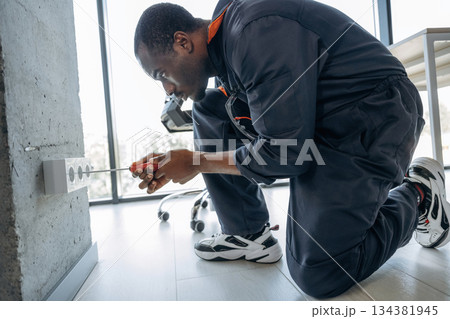 Process of installation of the socket. Repairman is indoors in the modern office 134381945