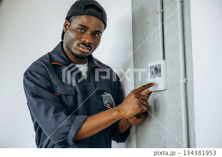 Examining the thermostat. Repairman is indoors in the modern office Examining the thermostat. Repairman is indoors in the modern office 134381953