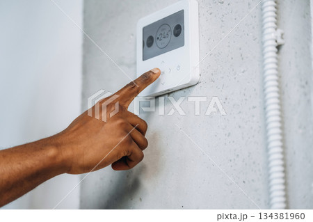 Thermostat on the wall. The repairman's hands fix it 134381960