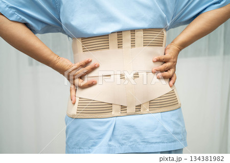 Asian senior pain back wearing elastic support belt with walker. 134381982