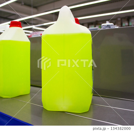Large yellow plastic container with a red cap standing on a store counter. Industrial cleaning or automotive liquid packaging Large yellow plastic container with a red cap standing on a store counter. Industrial cleaning or automotive liquid packaging 134382000
