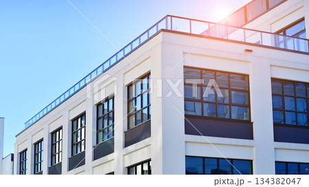 Office building in loft style. Facade of commercial office with windows. White walls of an industrial building. Office building in loft style. Facade of commercial office with windows. White walls of an industrial building. 134382047