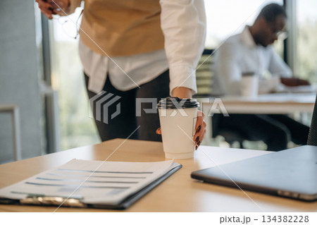 Woman is with cup of drink. Two business people are working together in the office 134382228