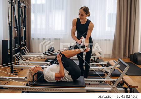 Legs exercise. Female trainer is helping old woman 134382453