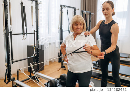 Rehabilitation concept. Female trainer is helping old woman to exercise Rehabilitation concept. Female trainer is helping old woman to exercise 134382481
