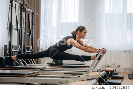 Side view, doing exercises. Young woman is in the gym with training equipment 134382627
