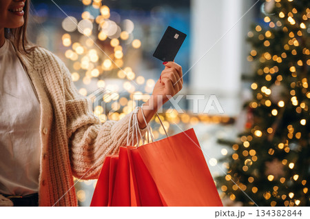 Ready for payment, holding credit card. New year shopping and presents. Woman is near the Christmas tree Ready for payment, holding credit card. New year shopping and presents. Woman is near the Christmas tree 134382844