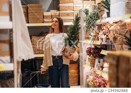 Small fir is in hand. Woman is in the shop with decoration, indoors 134382868