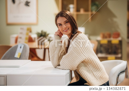 Beautiful smiling woman is sitting by the table on the kitchen Beautiful smiling woman is sitting by the table on the kitchen 134382871