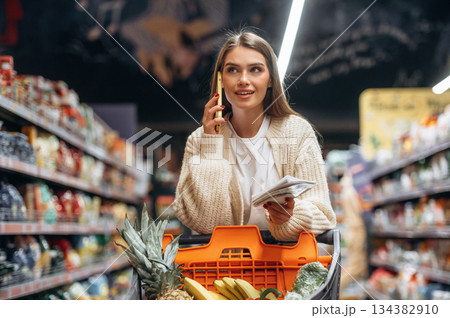 Yellow colored smartphone, talking. Beautiful woman is in the supermarket 134382910