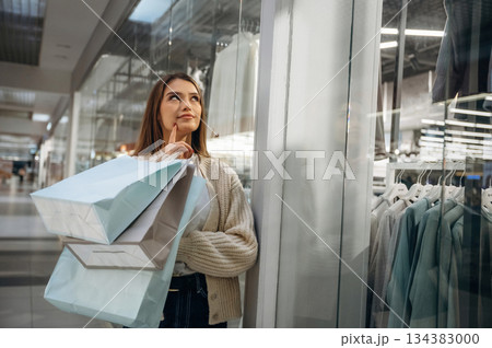 Thinking what to buy. Beautiful woman is in the mall, conception of shopping Thinking what to buy. Beautiful woman is in the mall, conception of shopping 134383000